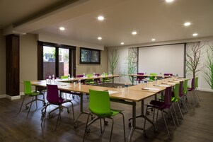 Un salón de conferencias con una larga mesa, varias sillas y una pantalla para proyector.
