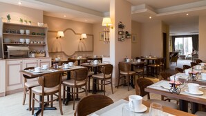 Un espace de restauration d'hôtel comprenant plusieurs tables et chaises, un coin café et des étagères murales ornées d'objets décoratifs.
