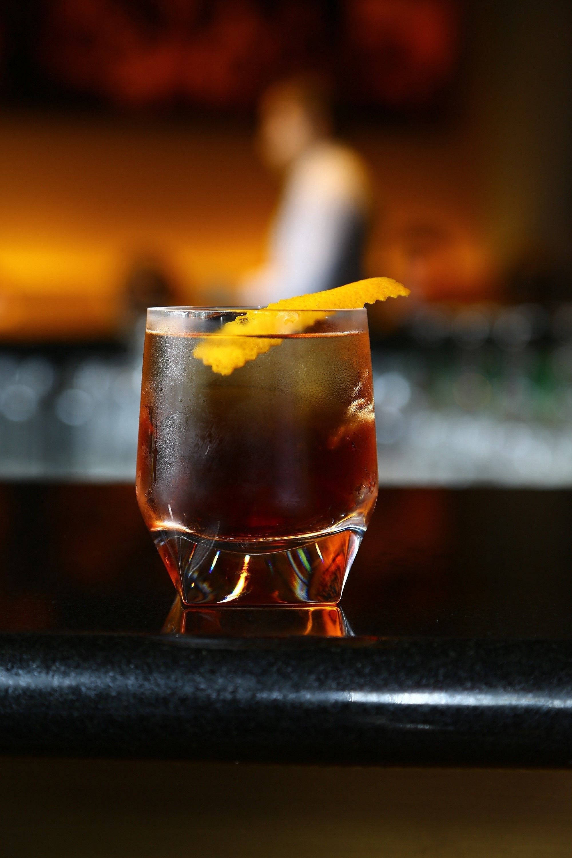 A glass of iced tea with a lemon slice garnish on a bar counter.