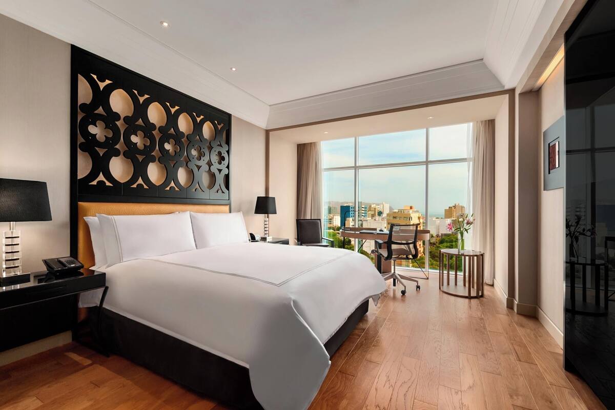 Ein modernes Hotelzimmer mit einem großen Bett, einem Schreibtisch und Blick auf die Stadt.