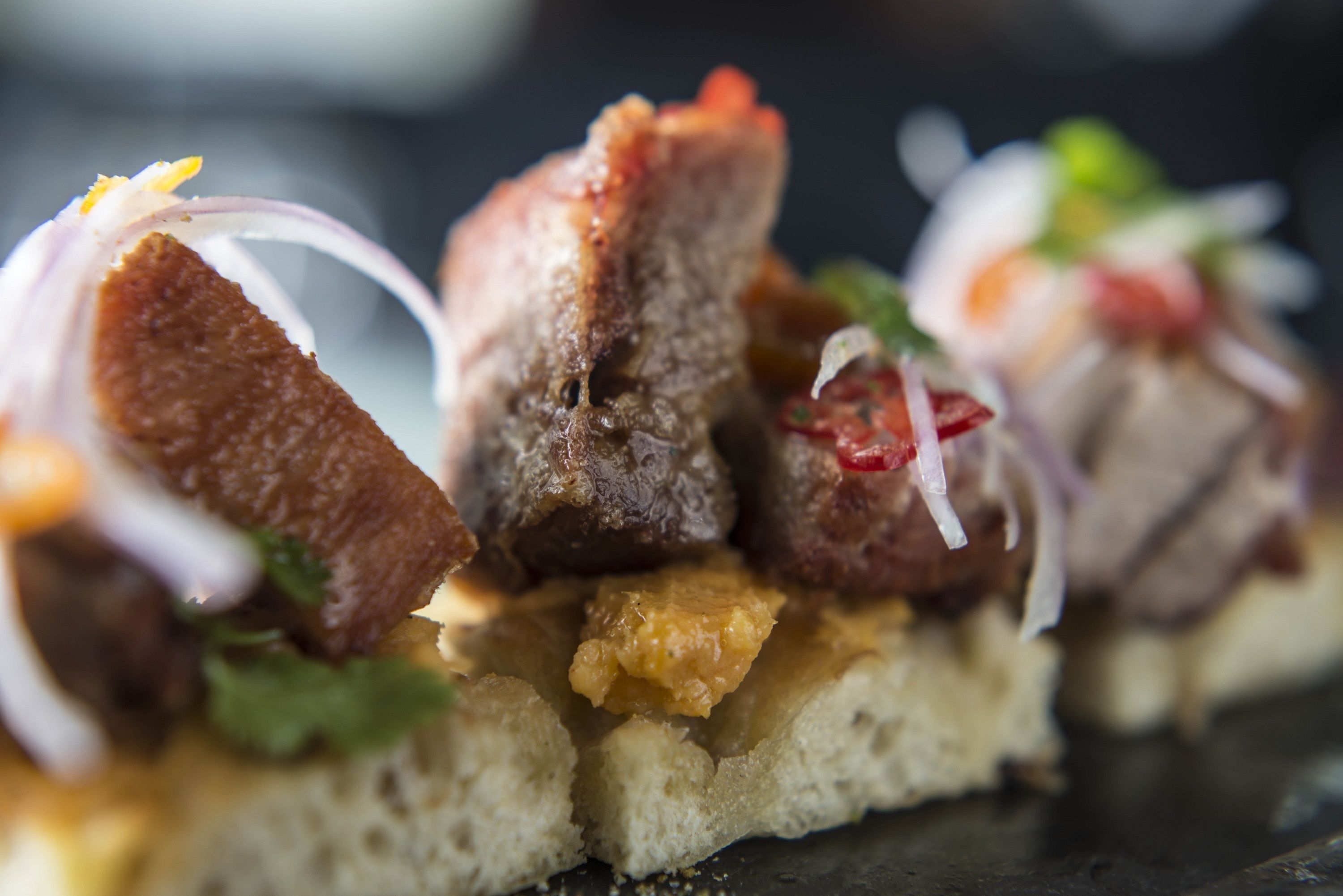 A close-up of a food item with bread, meat, and vegetables.