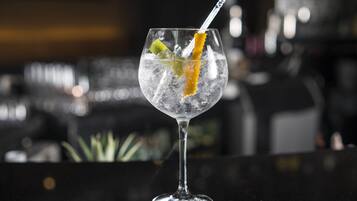 A cocktail glass with ice and a lemon slice on a bar counter.