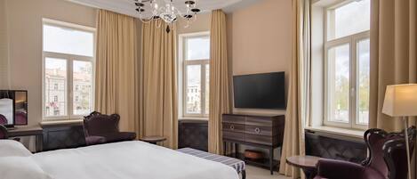 A hotel room with a large bed, a television, a desk, and a chair.