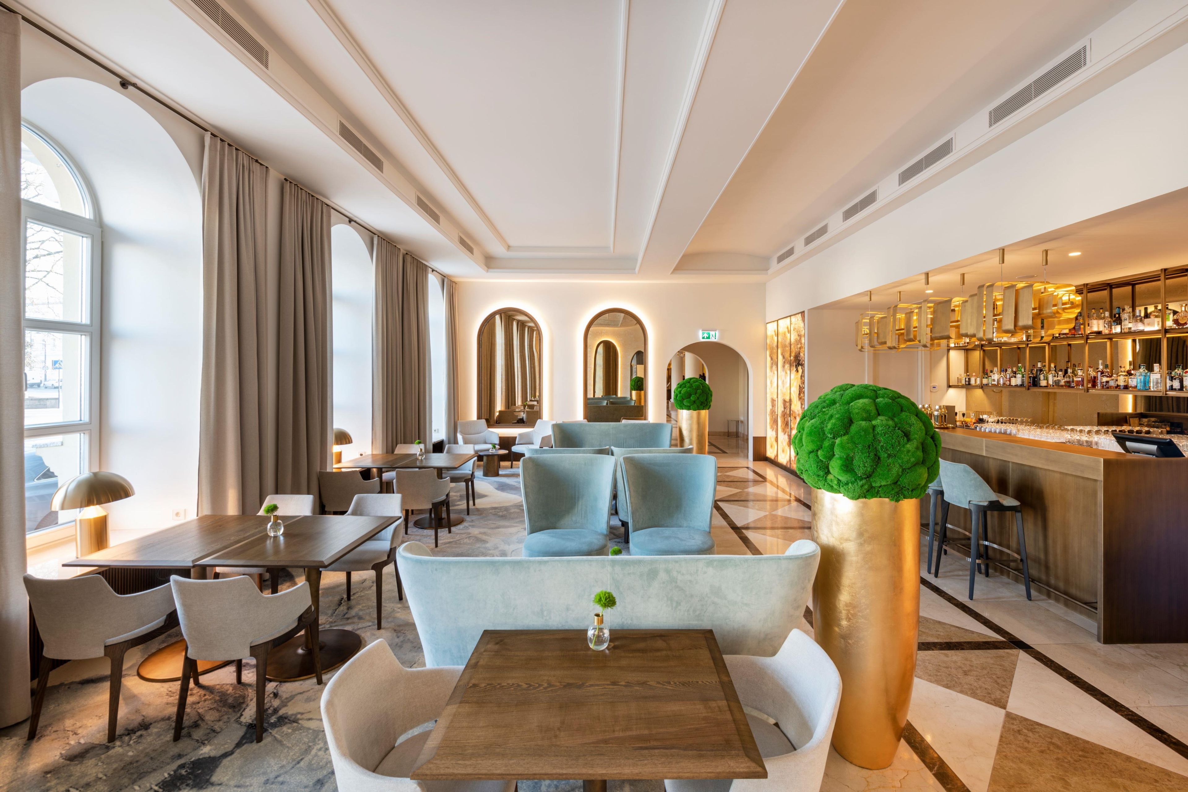 A hotel lobby with seating areas, a bar, and a large decorative plant.