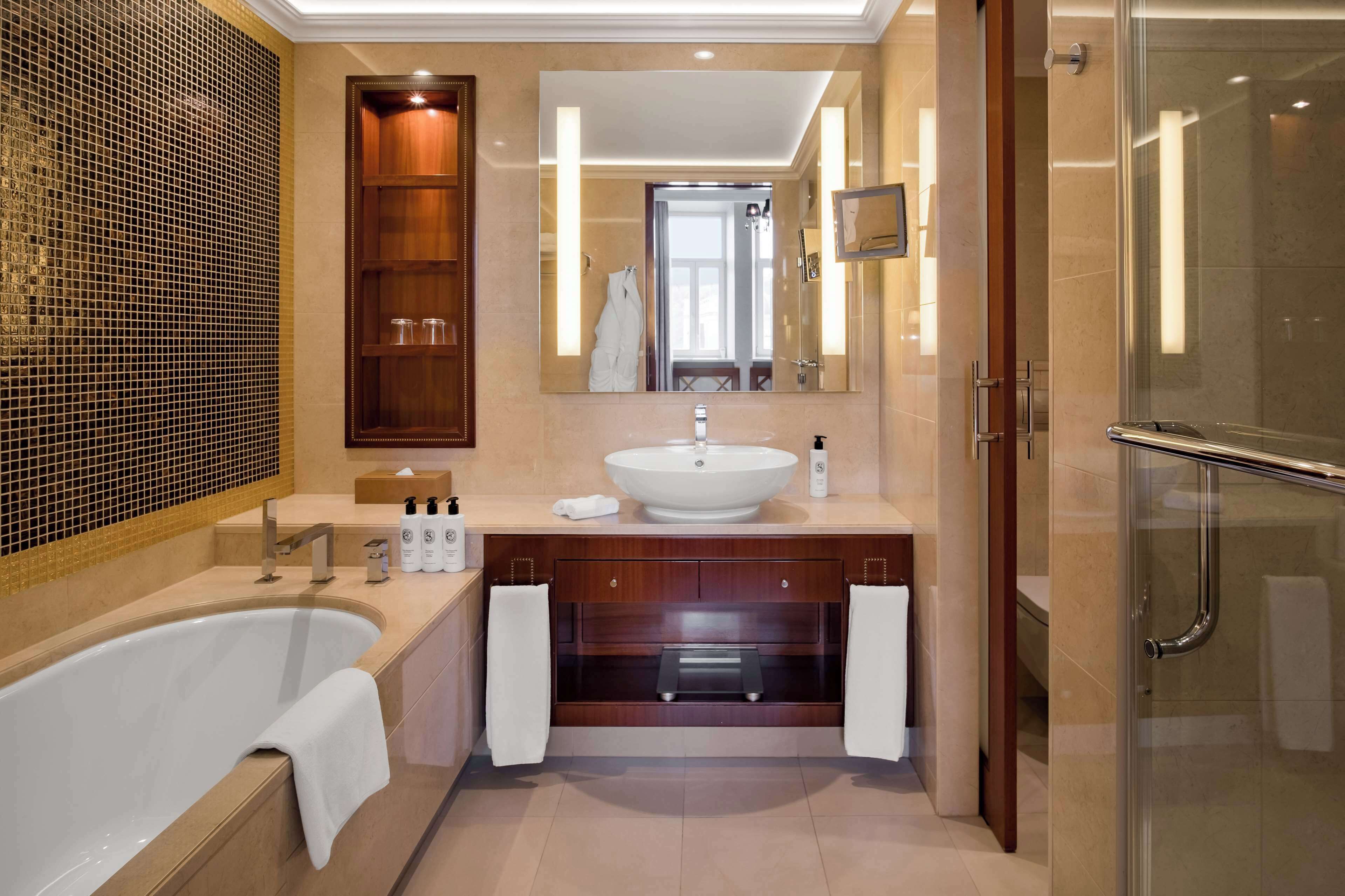 Un baño moderno con una bañera independiente, un espejo grande, un tocador con lavabo y un box de ducha de vidrio.