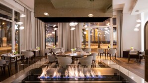 Un espace de restauration moderne avec des tables rondes, des chaises et un foyer central.