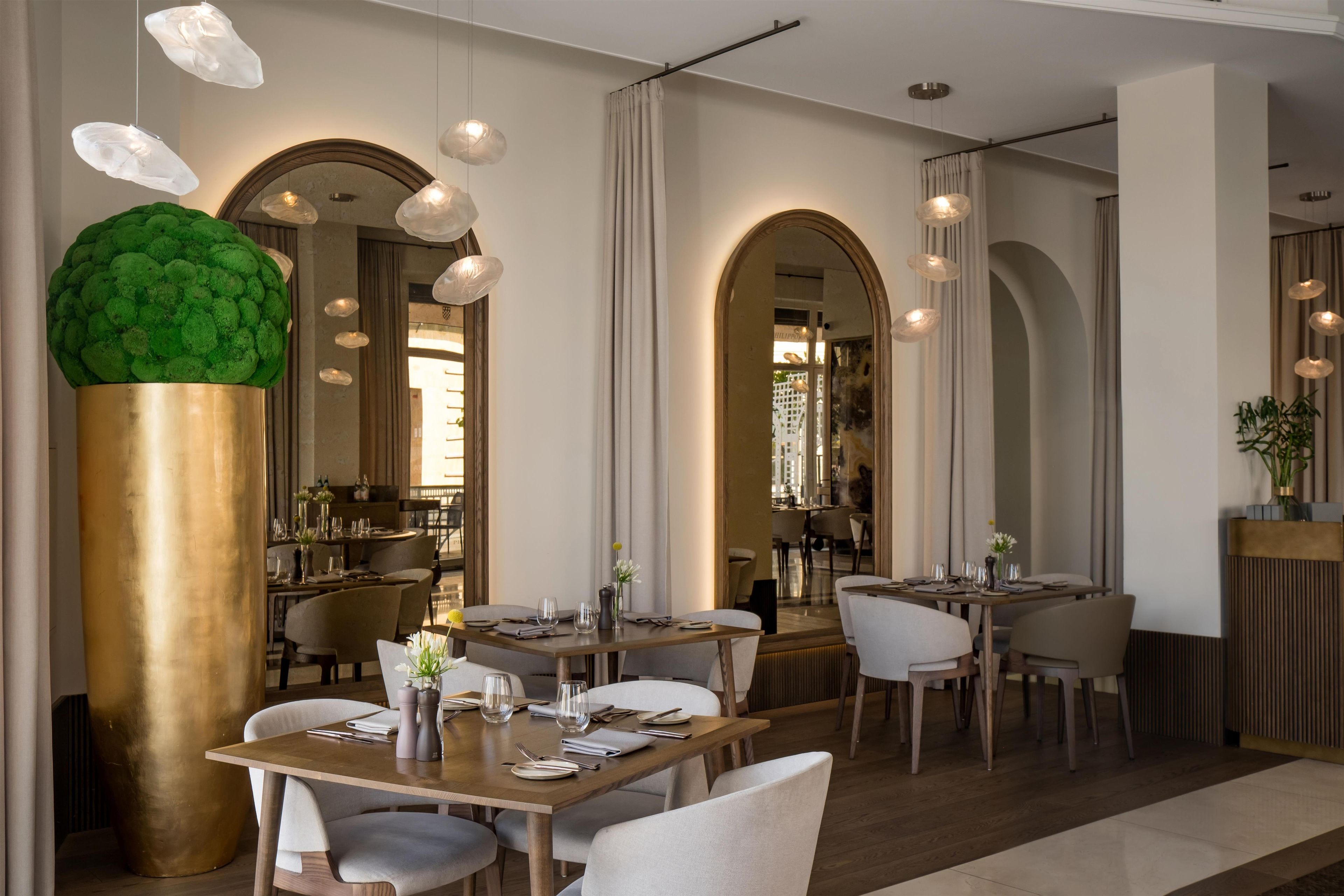 Un interno ristorante moderno con diversi tavoli, sedie e lampade a sospensione.