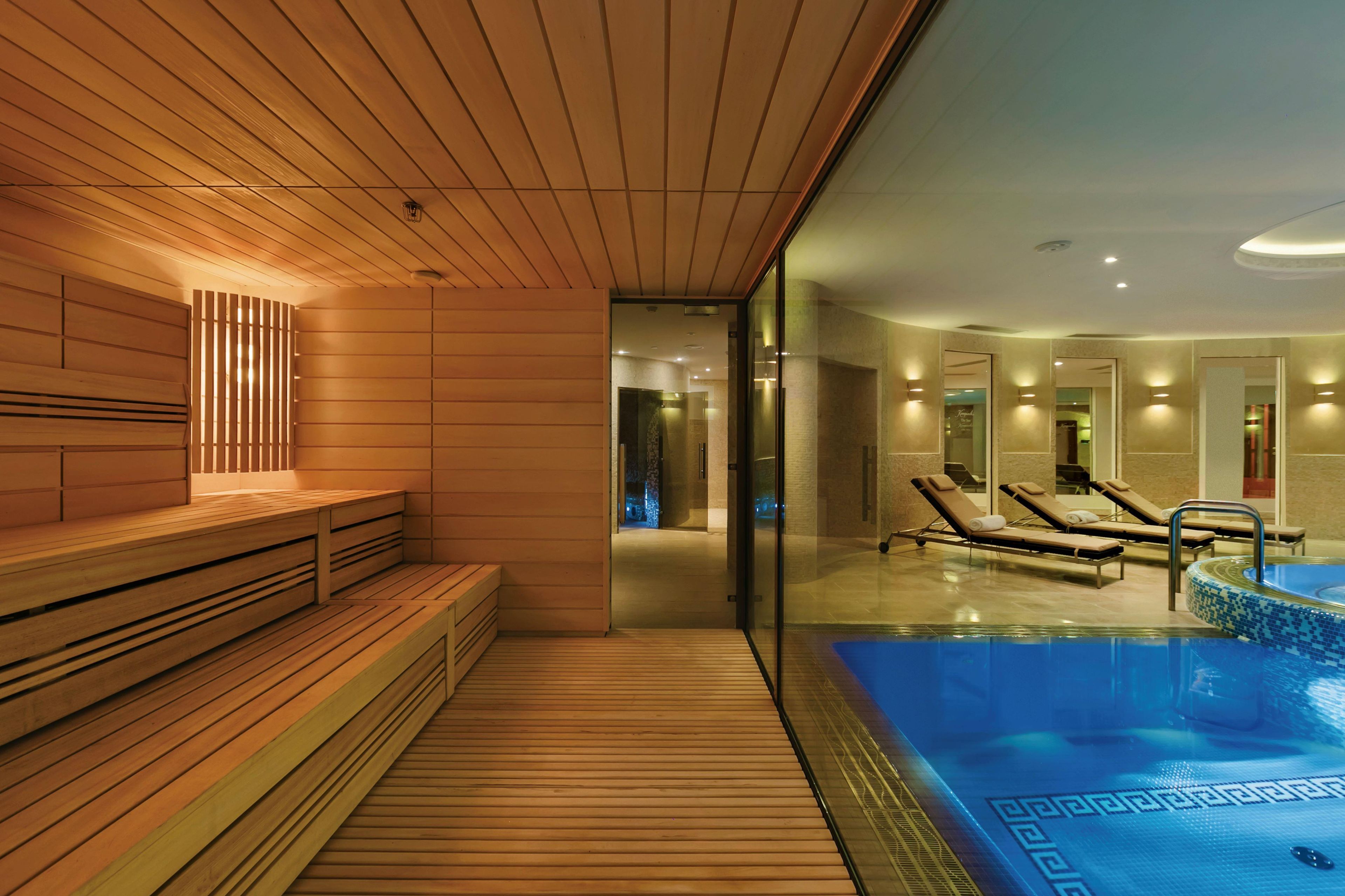 Ein moderner Spa-Bereich mit Holzliegen, einem Pool und Liegestühlen.