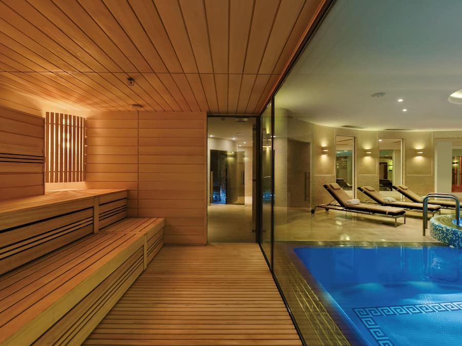 Ein moderner Spa-Bereich mit Holzliegen, einem Pool und Liegestühlen.