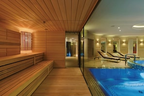 Un área de spa moderna con bancos de madera, piscina y tumbonas.