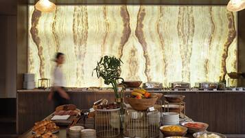 A buffet with various food items and a decorative wall in the background.