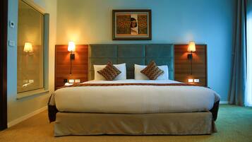 A hotel room with a large bed, two bedside lamps, a headboard with a picture, and a window with a view.