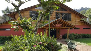 Un chalet en bois à la façade rouge, doté d’un porche abrité et d’une enseigne indiquant la présence d’un restaurant.