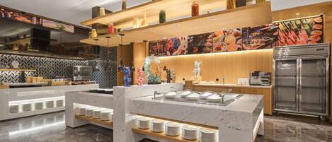 A modern kitchen with marble countertops, a buffet area, and a refrigerator.