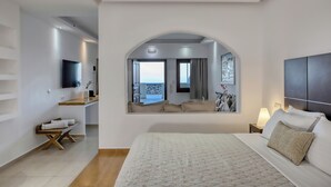 Una habitación de hotel moderna con una cama grande, un televisor montado en la pared, un escritorio pequeño y vistas amplias por una ventana grande.