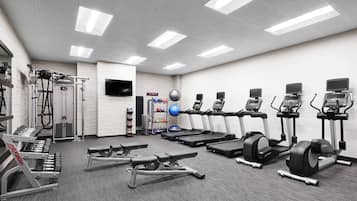 A gym with treadmills, elliptical machines, and free weights.