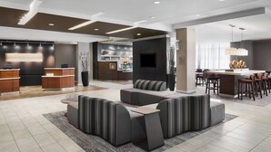 A modern hotel lobby with a reception desk, seating area, bar, and dining space. - Courtyard by Marriott Newark Downtown (Newark)