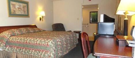 A hotel room with two beds, a desk, a chair, and a television.