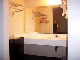 A hotel bathroom with a white sink, a mirror, and a towel rack.