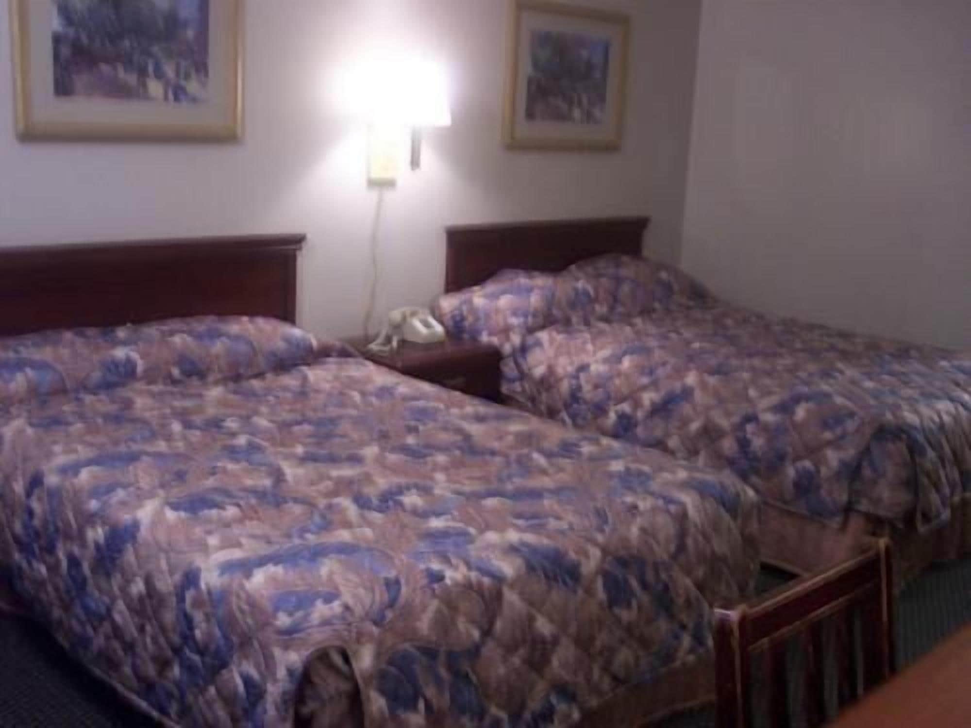 Habitació d'hotel amb dos llits, una tauleta de nit i una làmpada.