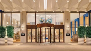 A hotel entrance with a revolving door, glass doors, and a modern ceiling design. - Grand Metropark Universal Dinosaur Town Hotel (Changzhou)