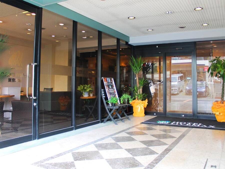 Entrada de hotel com portas de vidro, balcão de recepção e piso ladrilhado.