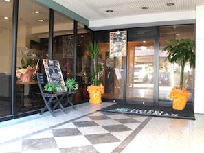 A hotel entrance with a check-in desk, potted plants, and a tiled floor. - HOTEL LiVEMAX Tokyo Kiba (Tokyo)