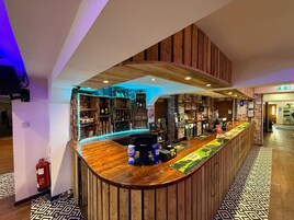 Un área de bar con paneles de madera, un menú para perros y una variedad de botellas y vasos en estanterías.