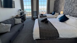 A hotel room with two beds, a sofa, a TV, and a balcony with a view of the sea. - The Jubilee Hotel West- with Spa Facilities (Weymouth)