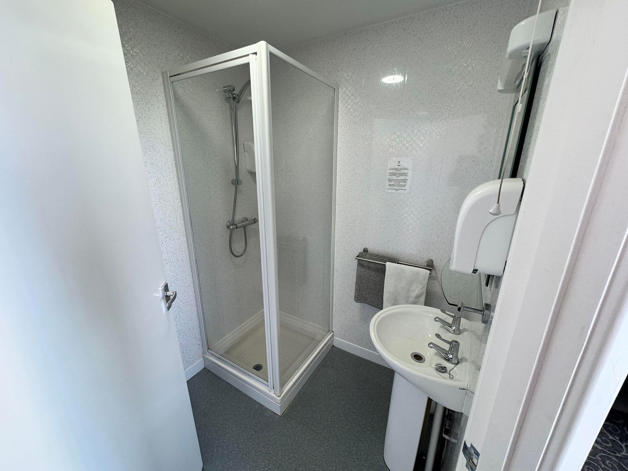 A modern bathroom with a glass-enclosed shower, a sink, and a mirror.