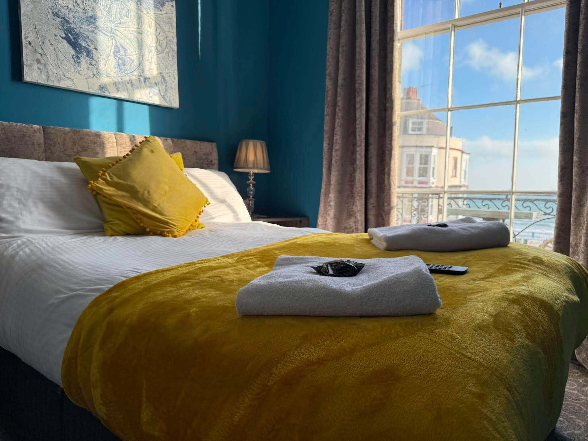 A hotel room with a bed, a window with a view, and a lamp.