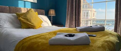 A hotel room with a bed, a window with a view, and a lamp.