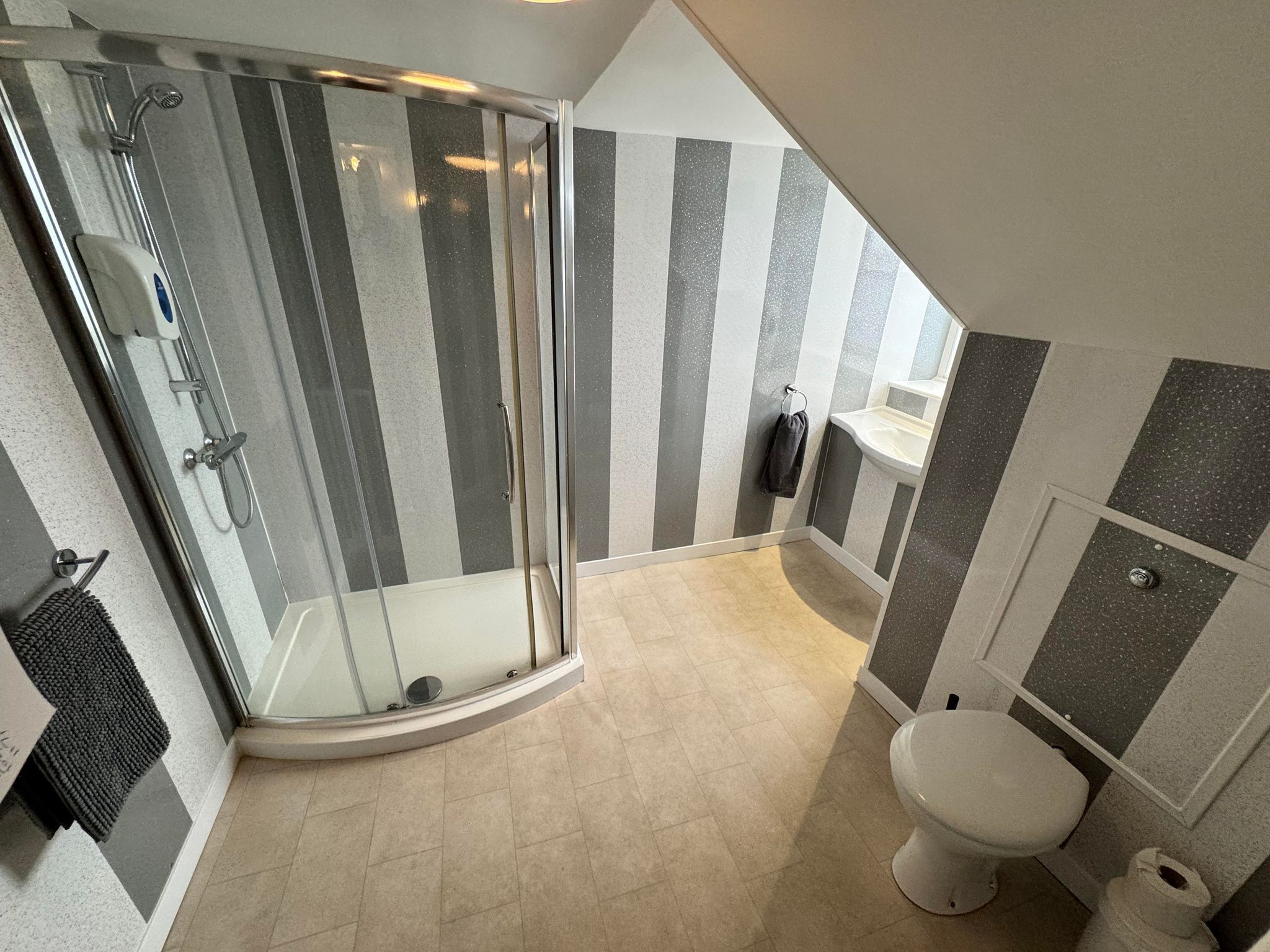 Un baño moderno con cabina de ducha de vidrio, inodoro y lavamanos.