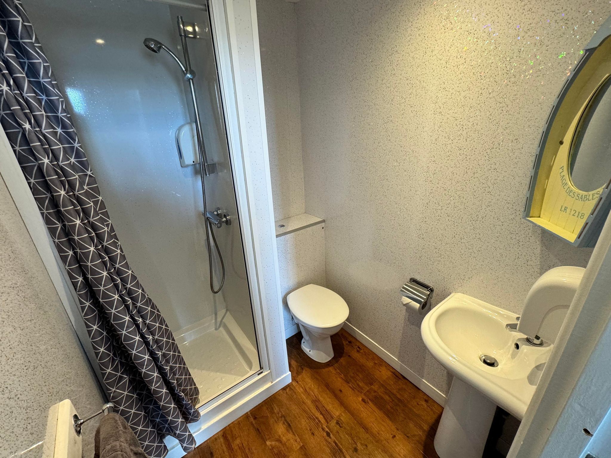 Une salle de bain avec une douche à parois de verre, des toilettes et un lavabo.