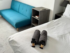 Una habitación de hotel con una cama, un sofá azul, una mesita de noche y una lámpara.