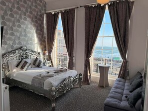 A bedroom with a large bed, a view of the sea, and a balcony with a table. - The Jubilee Hotel West- with Spa Facilities (Weymouth)