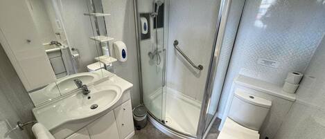 A modern bathroom with a glass-enclosed shower, a white sink, and a toilet.