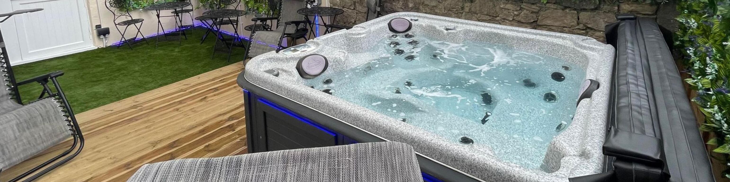 A hot tub with a stone exterior, surrounded by a wooden deck and outdoor furniture.