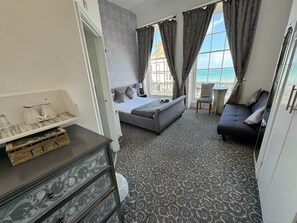 Une chambre d’hôtel avec un lit, un canapé, une petite table et une vue sur la mer.