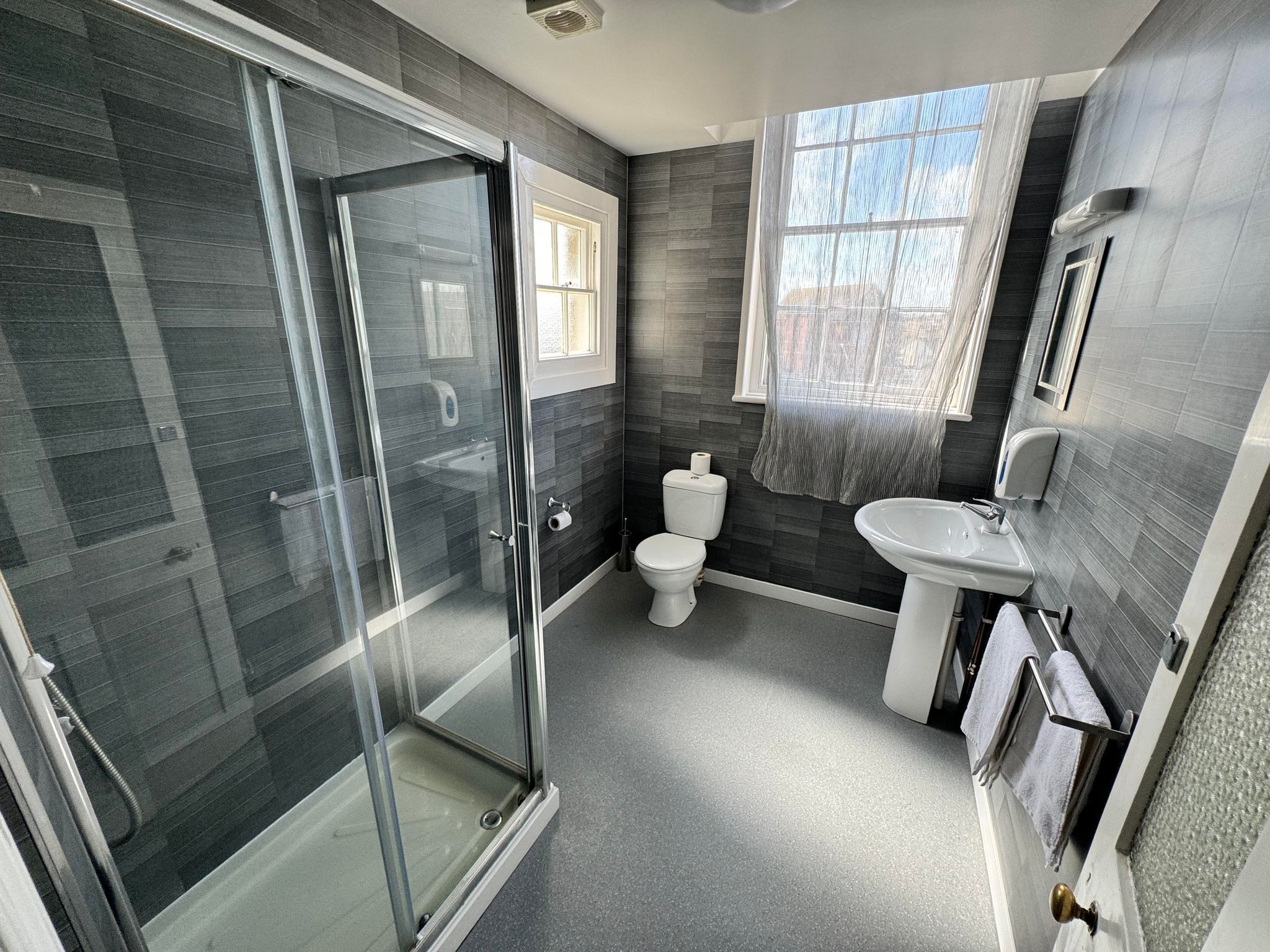 A modern bathroom with a glass shower enclosure, a toilet, and a sink.