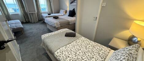 Une chambre d’hôtel avec deux lits, un coin salon et vue sur la mer.
