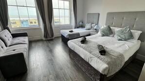 A hotel room with two beds, a sofa, and large windows with curtains. - The Jubilee Hotel West- with Spa Facilities (Weymouth)