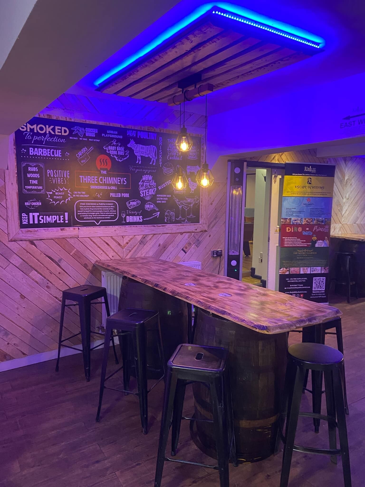 Angolo bar con bancone in legno, sgabelli e lavagna per il menu.
