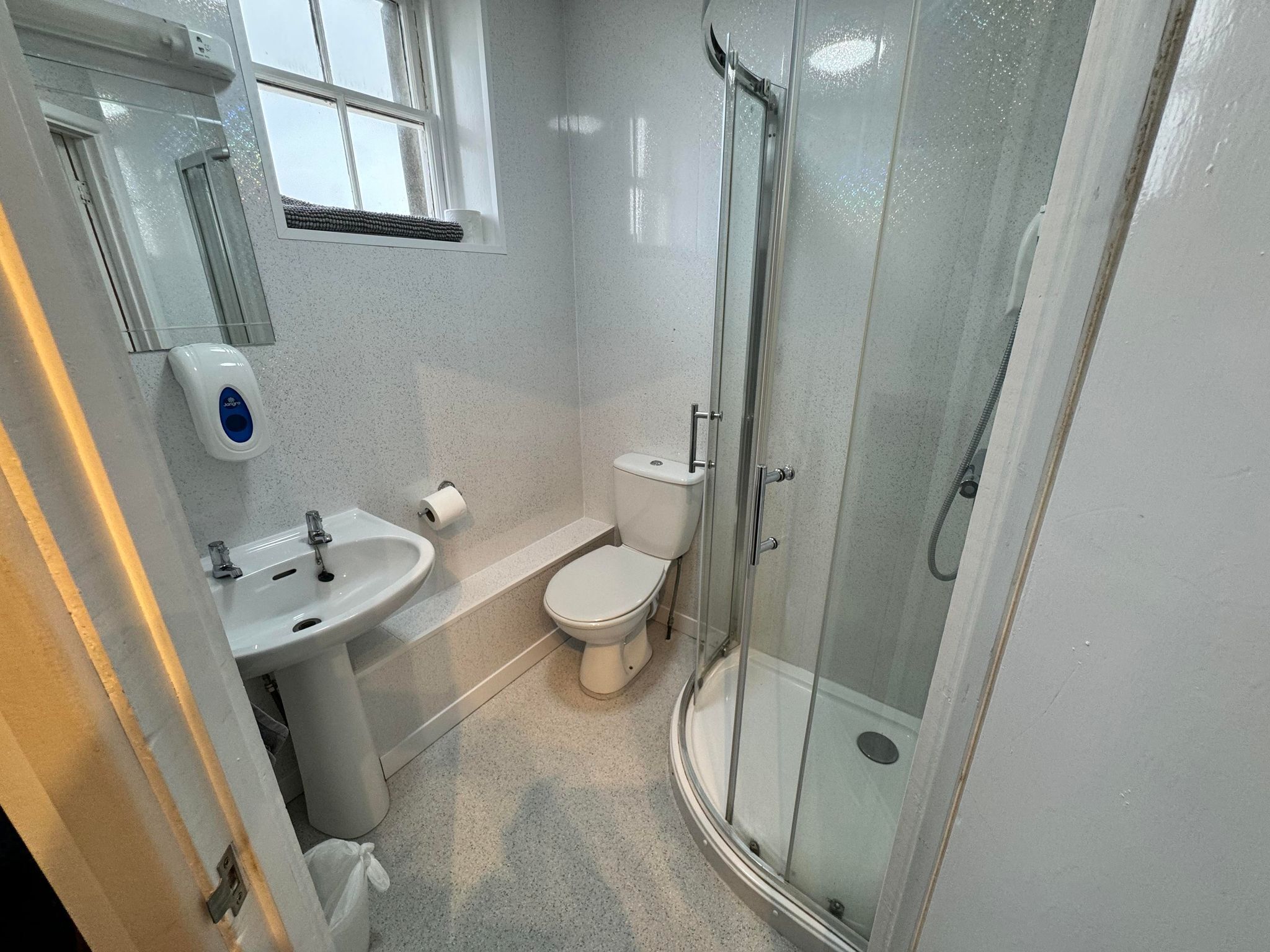A compact bathroom with a glass-enclosed shower, a toilet, and a sink.