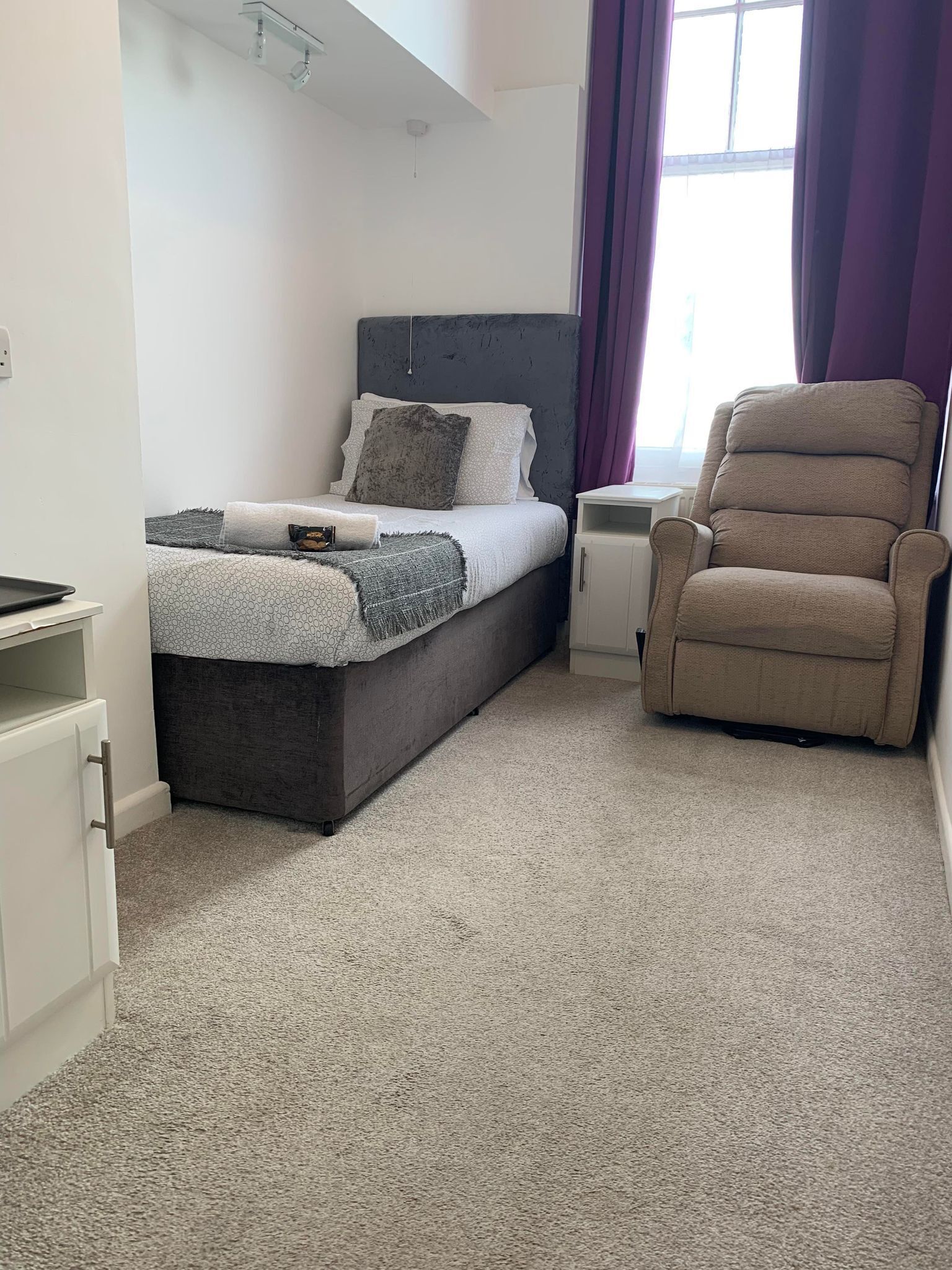 Un dormitorio con cama, una silla, una mesita de noche y una pequeña mesa.