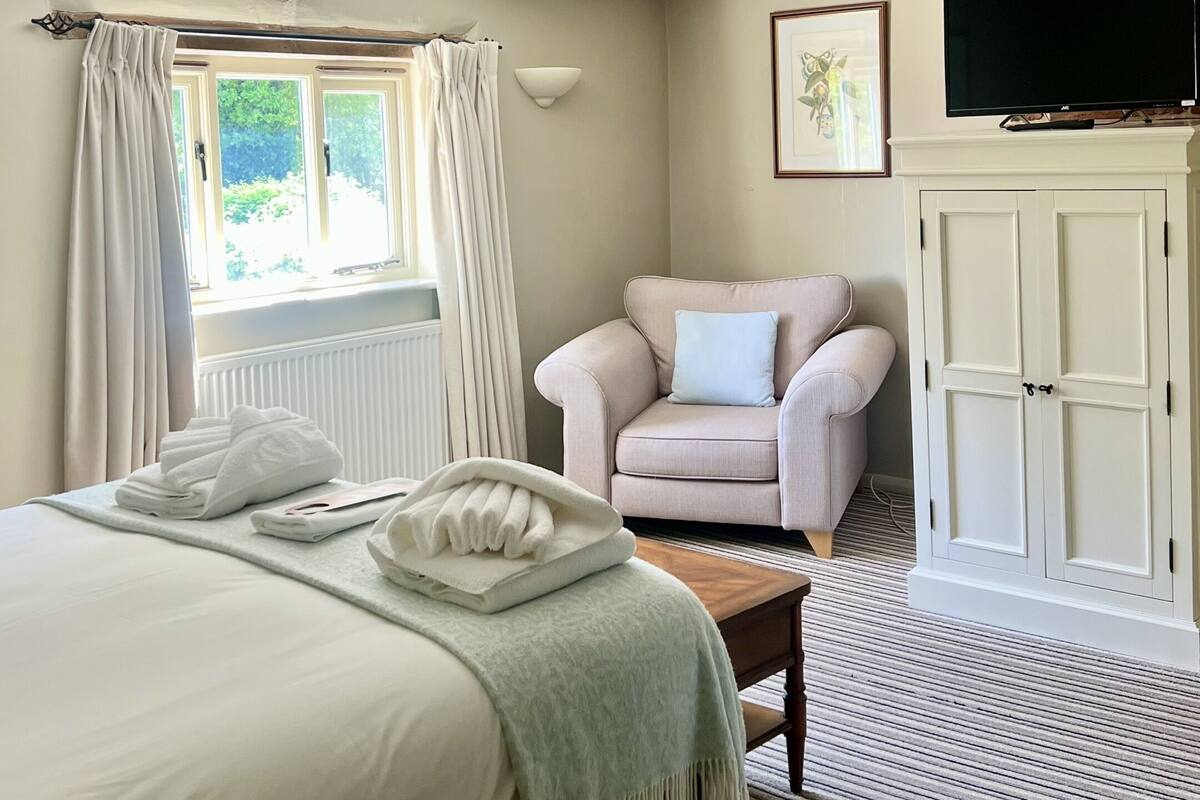 A bedroom with a bed, a chair, a television, and a wardrobe.