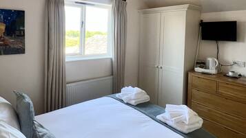 A hotel room with a bed, a dresser, a television, and a window with curtains.