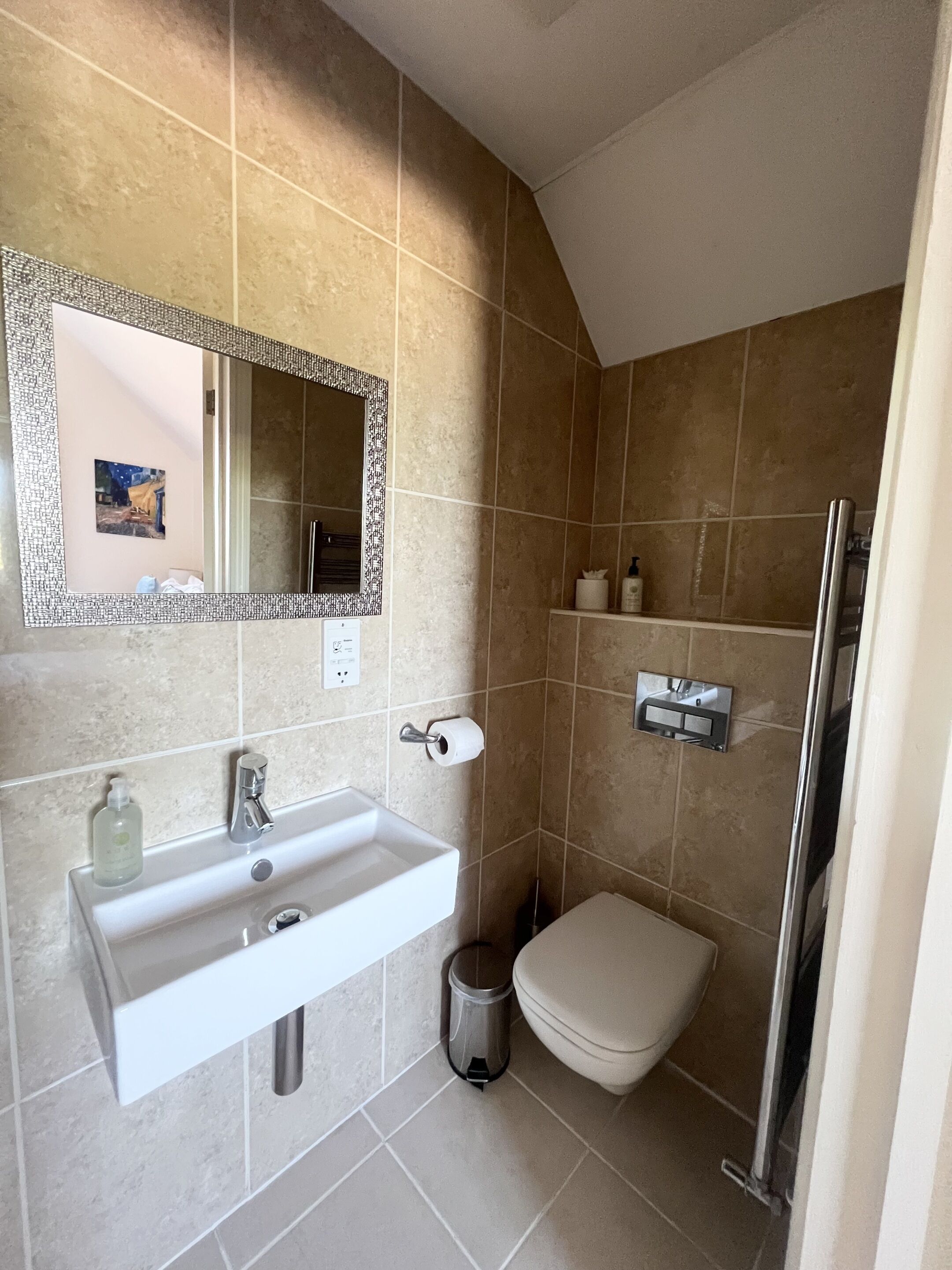 A modern bathroom with a white sink, mirror, and toilet.