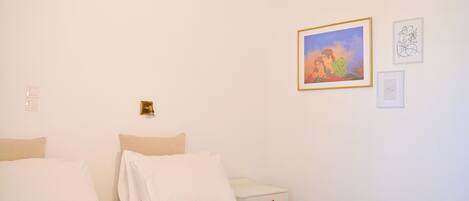 A hotel room with a bed, a nightstand, and a wall with framed artwork.