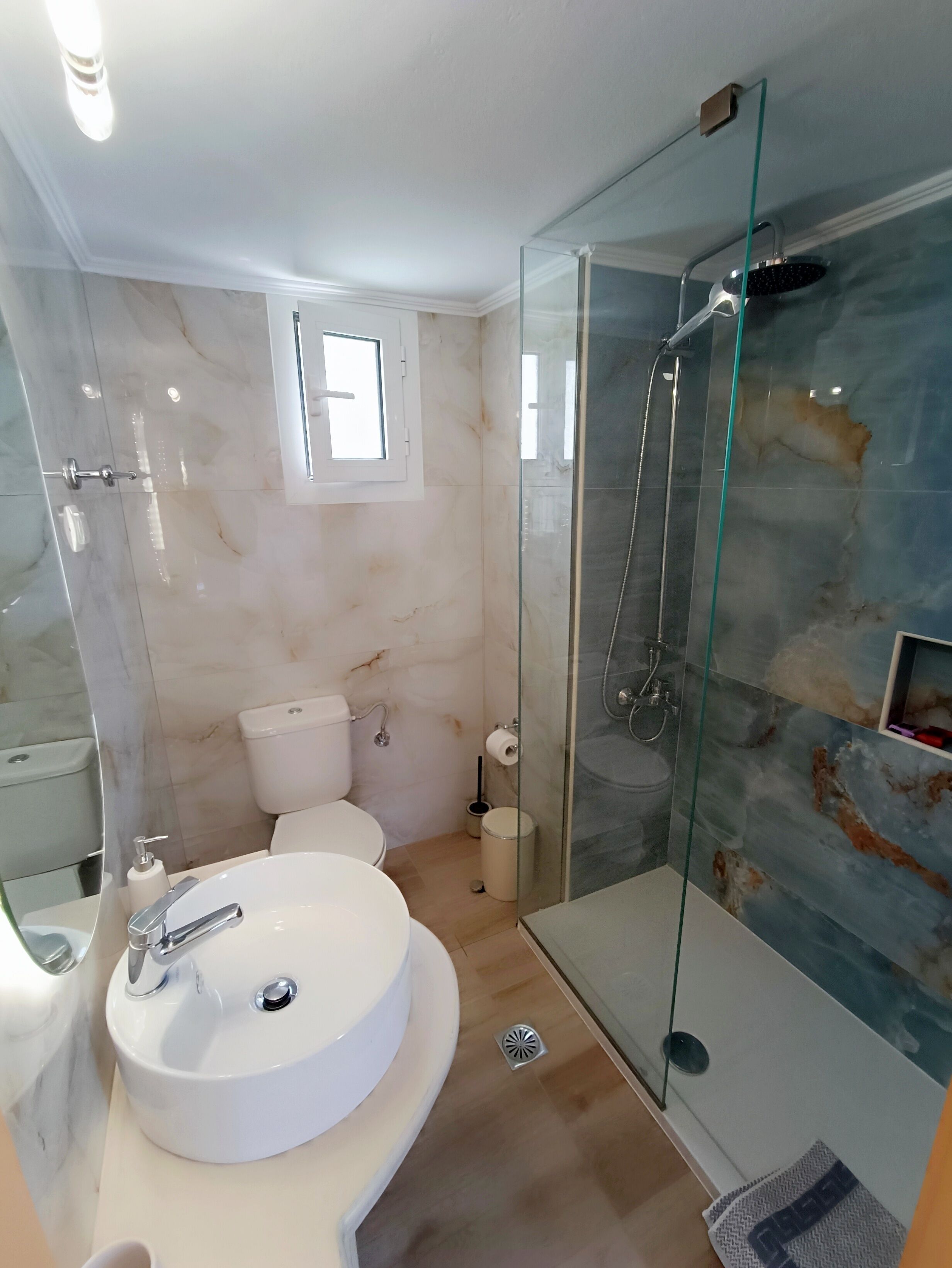 Un bagno moderno con doccia vetrata, lavandino bianco e servizi igienici.